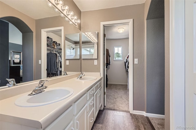 9890 Gaylord St, Thornton, CO 80229 - bathroom featuring double vanity, wood finished floors, a walk in closet, and a textured wall