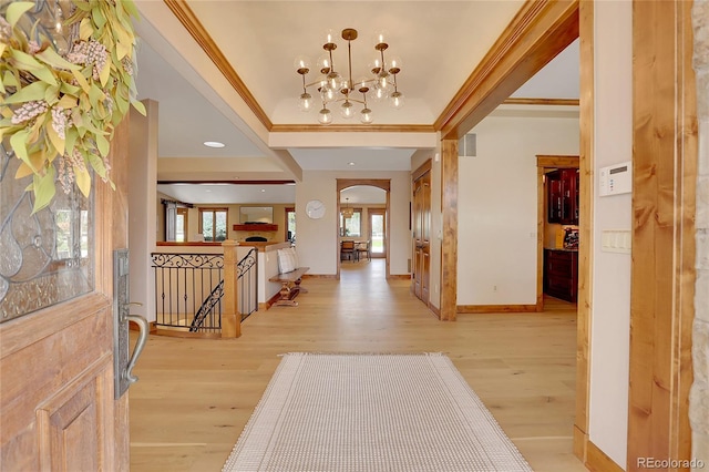 foyer entrance featuring a chandelier, crown molding, and light hardwood / wood-style flooring