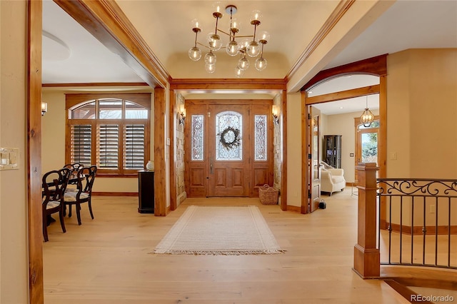 foyer entrance featuring a healthy amount of sunlight, light hardwood / wood-style floors, beam ceiling, and an inviting chandelier