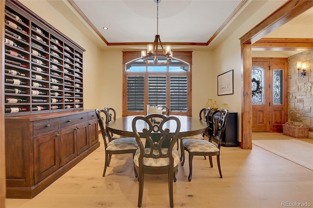 dining area featuring crown molding, a raised ceiling, light hardwood / wood-style flooring, and an inviting chandelier