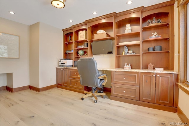 home office with built in desk and light hardwood / wood-style floors