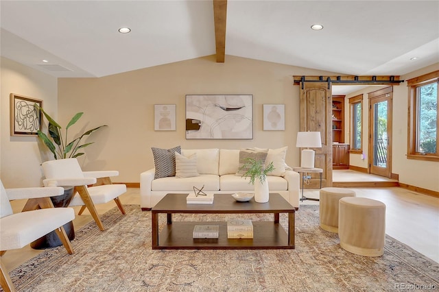 living room with a barn door and lofted ceiling with beams