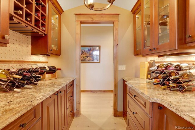 kitchen with backsplash, light stone counters, and light wood-type flooring