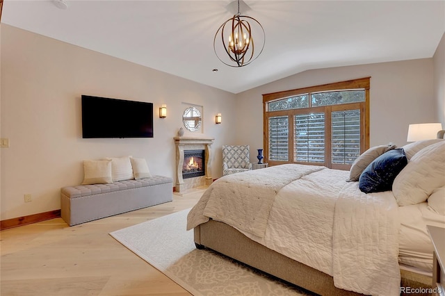 bedroom featuring light hardwood / wood-style floors, vaulted ceiling, and an inviting chandelier