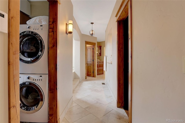 laundry room featuring stacked washer / drying machine and light tile patterned flooring