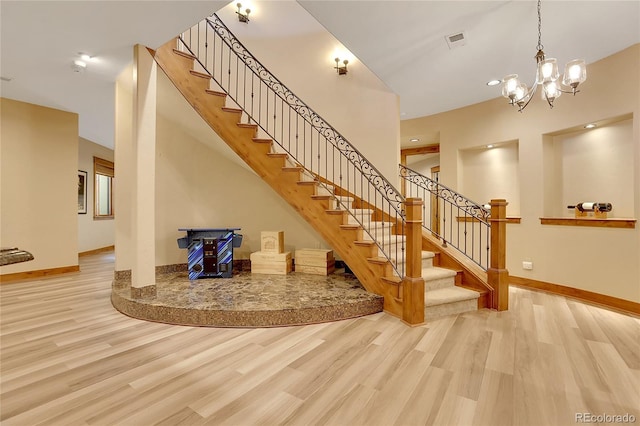 stairs featuring hardwood / wood-style floors and a chandelier