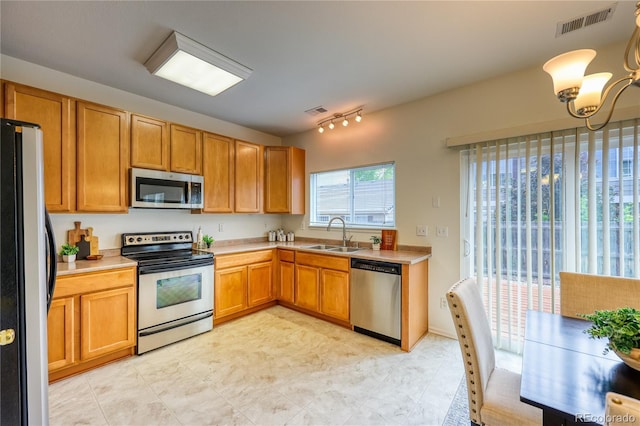 7345 S Nucla St, Aurora, CO 80016 - kitchen with appliances with stainless steel finishes, light countertops, a chandelier, and brown cabinetry