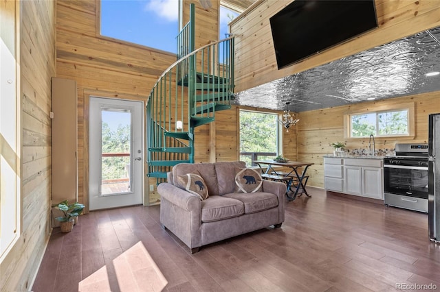 living room featuring dark hardwood / wood-style flooring, wood walls, a towering ceiling, and a wealth of natural light