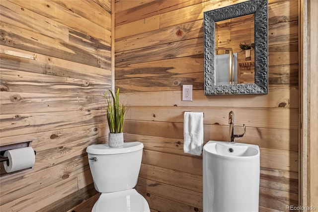 bathroom with wood walls and toilet