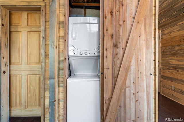 clothes washing area with stacked washing maching and dryer and wood-type flooring