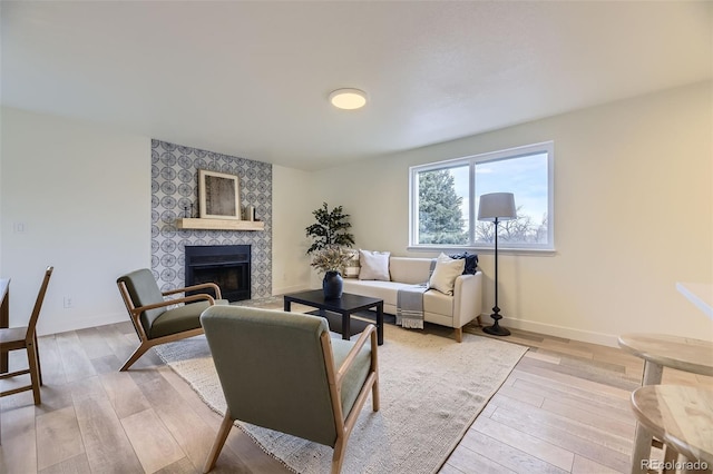 living area featuring baseboards, a fireplace, and light wood finished floors