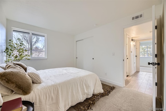 bedroom featuring light carpet, visible vents, and baseboards