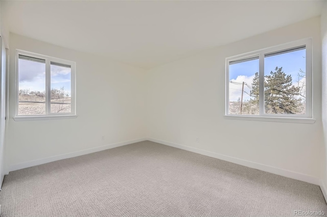 empty room with baseboards, a wealth of natural light, and light colored carpet