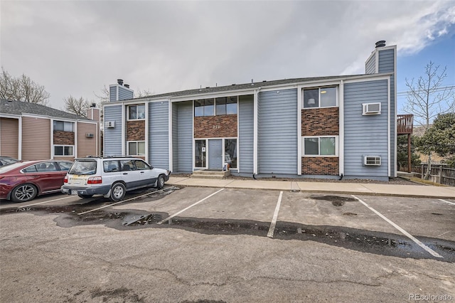 view of property featuring entry steps, uncovered parking, and central air condition unit