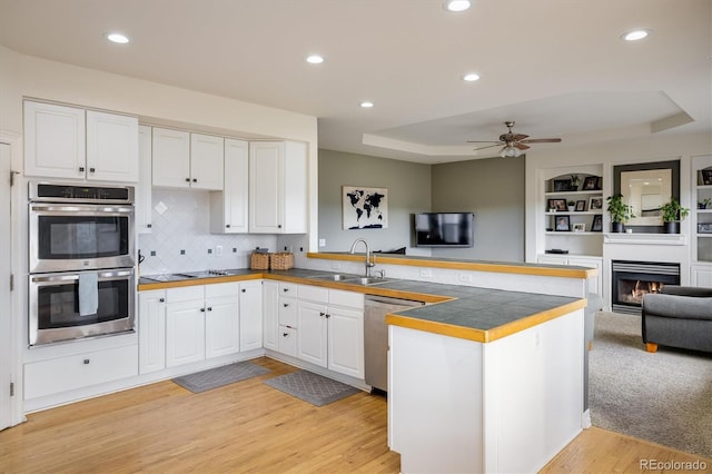 kitchen featuring kitchen peninsula, appliances with stainless steel finishes, white cabinetry, and sink