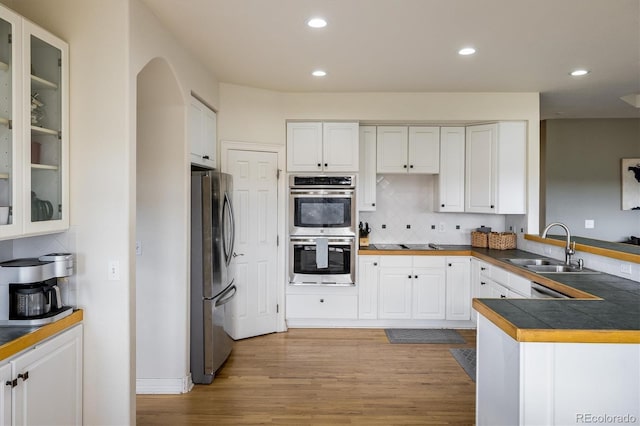 kitchen featuring sink, stainless steel appliances, kitchen peninsula, white cabinets, and hardwood / wood-style flooring