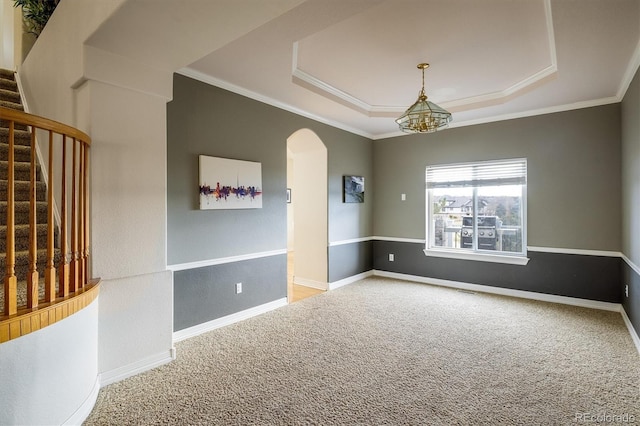 empty room featuring carpet, a notable chandelier, a raised ceiling, and ornamental molding