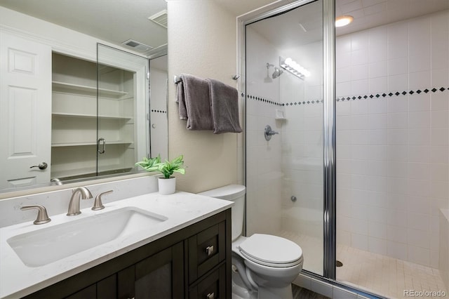 bathroom featuring a shower with door, vanity, and toilet