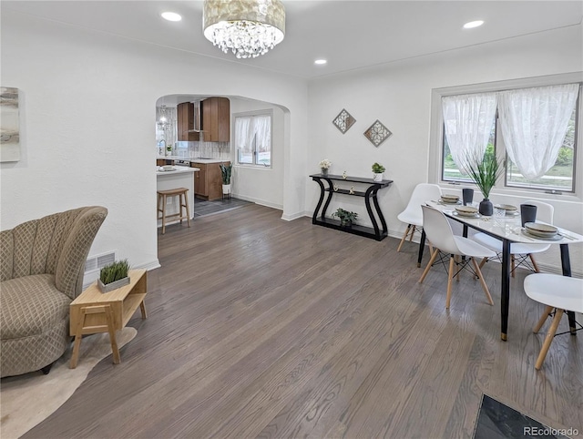 dining space with recessed lighting, baseboards, a chandelier, arched walkways, and dark wood-style floors