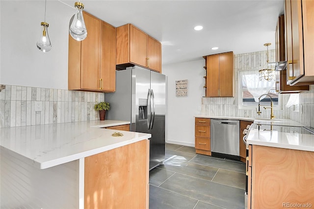 kitchen featuring a peninsula, appliances with stainless steel finishes, decorative light fixtures, and backsplash