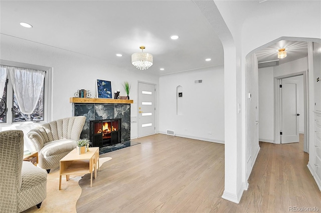 living area featuring light wood-style flooring, a high end fireplace, visible vents, and recessed lighting