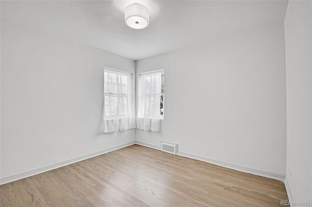 spare room featuring baseboards, visible vents, and wood finished floors