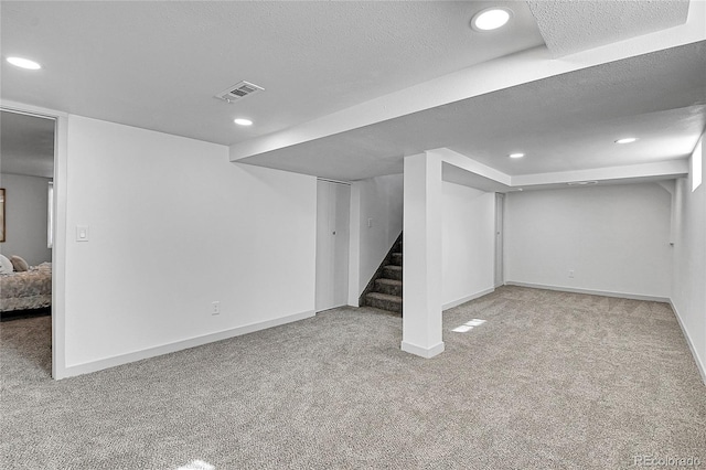 finished basement featuring recessed lighting, stairway, visible vents, and carpet floors