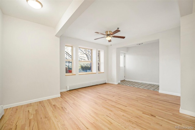 empty room with a baseboard radiator, light wood finished floors, ceiling fan, and baseboards