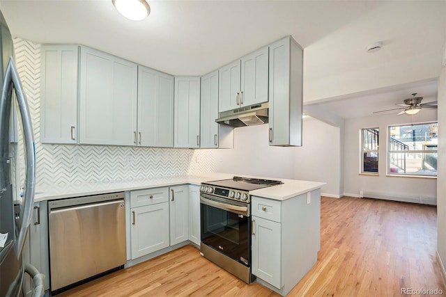 kitchen featuring light countertops, light wood-type flooring, a peninsula, under cabinet range hood, and stainless steel appliances