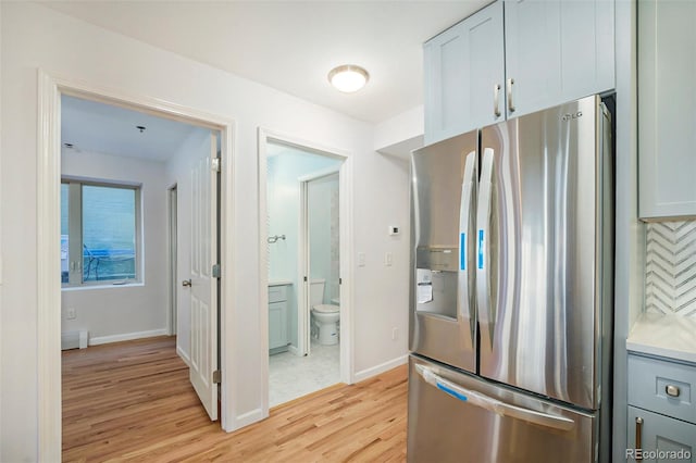 kitchen featuring light countertops, light wood-style floors, stainless steel fridge with ice dispenser, and baseboards