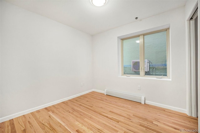 unfurnished room with baseboards, a baseboard heating unit, and wood finished floors