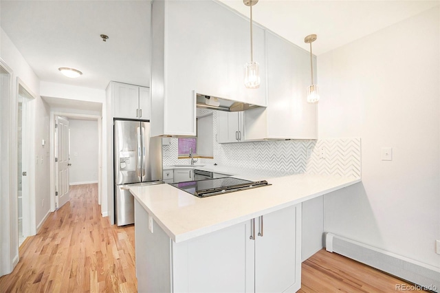 kitchen featuring stainless steel refrigerator with ice dispenser, a sink, a baseboard radiator, a peninsula, and backsplash
