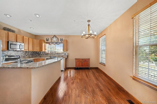 32401 E 147th Ave, Brighton, CO 80603 - kitchen with appliances with stainless steel finishes, dark wood-style flooring, a chandelier, decorative backsplash, and light stone counters