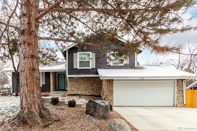 tri-level home featuring a garage, stone siding, and driveway