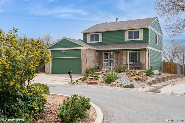 traditional-style home featuring fence, covered porch, brick siding, concrete driveway, and an attached garage