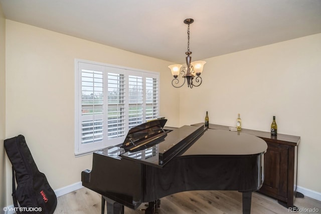 sitting room featuring baseboards, light wood finished floors, and a notable chandelier