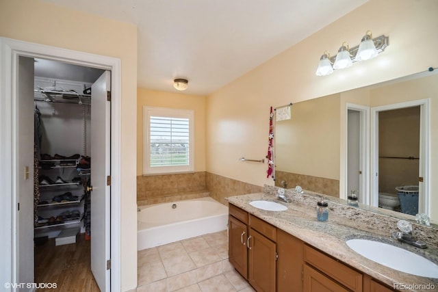full bath featuring a sink, a walk in closet, and a bath
