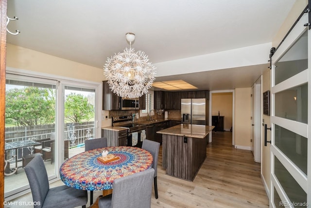 dining space featuring an inviting chandelier, light wood-style flooring, and baseboards