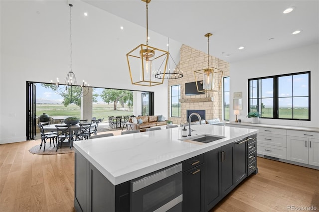 kitchen featuring a fireplace, light wood-type flooring, a center island with sink, and stainless steel microwave