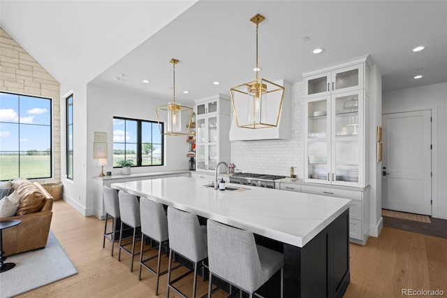 kitchen featuring white cabinetry, a kitchen island with sink, light hardwood / wood-style flooring, and pendant lighting