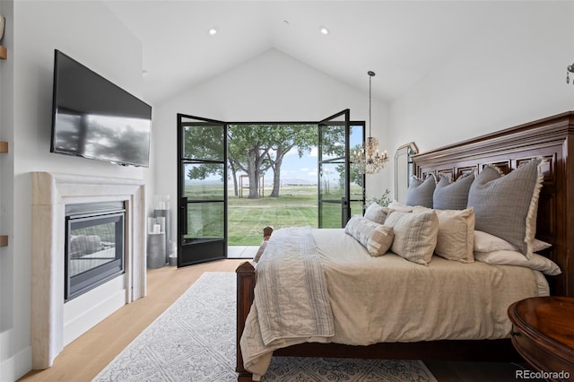 bedroom with high vaulted ceiling, access to exterior, and light hardwood / wood-style flooring