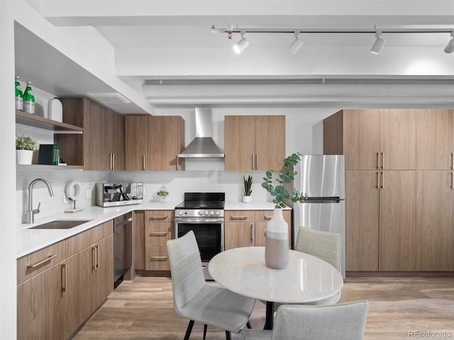 kitchen featuring light wood-style flooring, open shelves, a sink, appliances with stainless steel finishes, and wall chimney exhaust hood