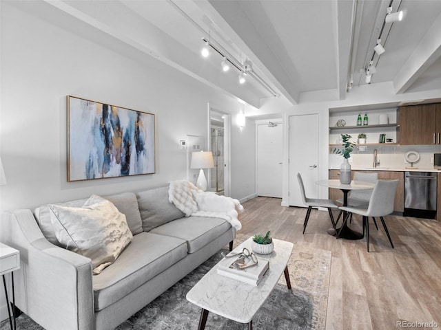 living room with built in features, light wood-style flooring, rail lighting, wet bar, and beam ceiling