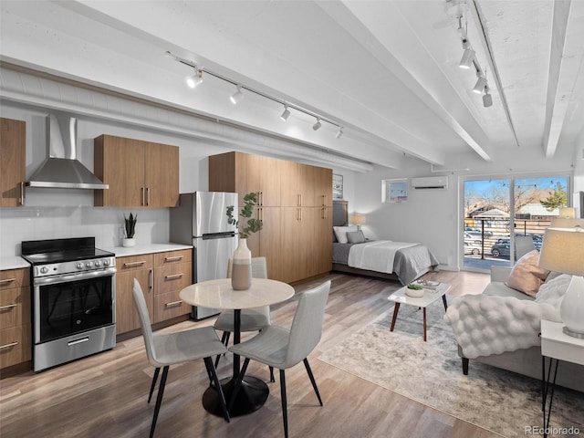 kitchen featuring open floor plan, stainless steel appliances, wall chimney range hood, and brown cabinetry