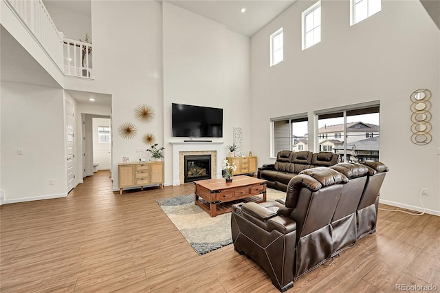 living room featuring light hardwood / wood-style floors, a tile fireplace, and a towering ceiling