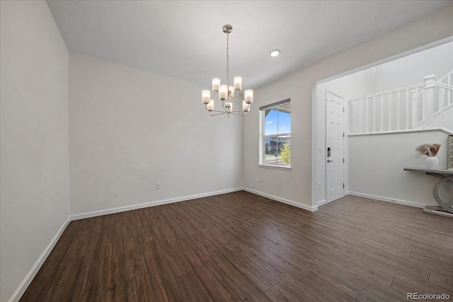 empty room featuring dark wood-type flooring and a chandelier