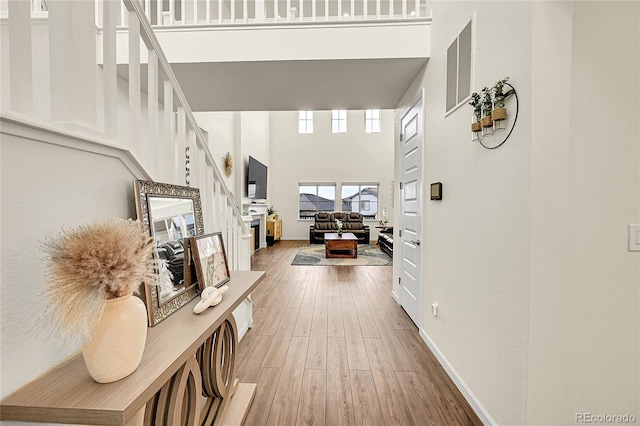 hallway with a towering ceiling and hardwood / wood-style flooring