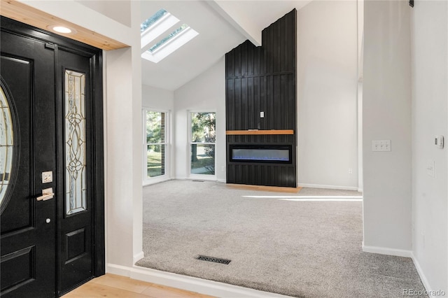 carpeted entryway featuring a fireplace and lofted ceiling with skylight