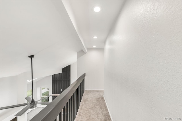 hallway featuring lofted ceiling and light colored carpet