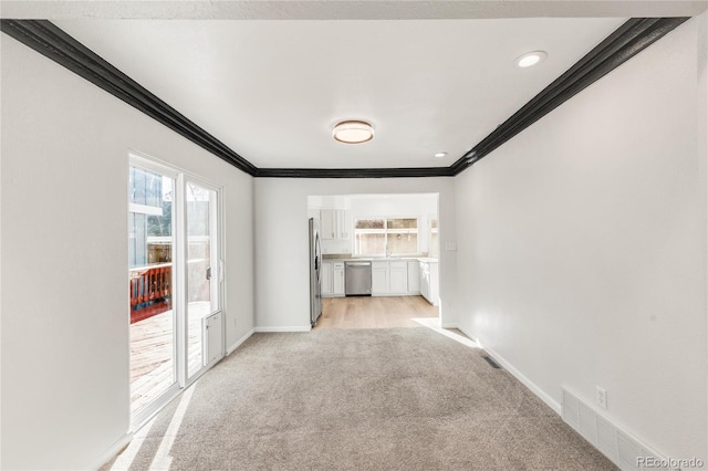 unfurnished living room featuring ornamental molding and light colored carpet